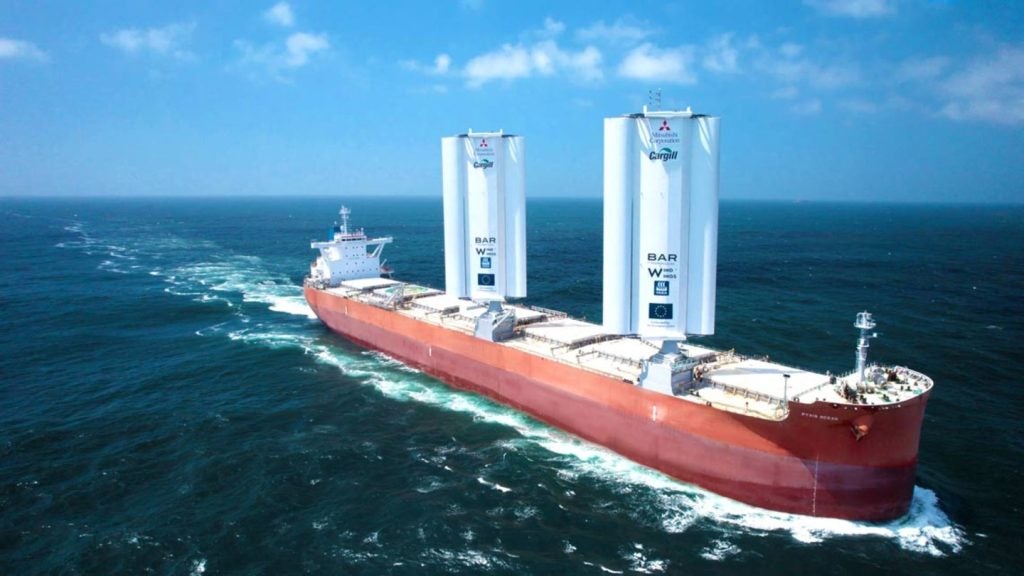 The Pyxis Ocean cargo vessel sailing in the water fitted with the WindWings, two large white rectangular towers with curved solid wings on either side.